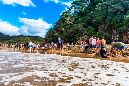 COROMANDEL, NEW ZEALAND - OCTOBER 13, 2018: Tourists dig holes in the volcanic sand on the Hot Water beachのeditorial素材