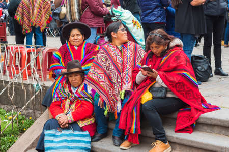 CUSCO, PERU - JUNE 26, 2019: Women in national costumes sit on the steps, San Cristobal Celebracion