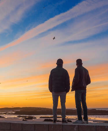 Two men at sunset on the ocean, Essaouira, Moroccoの写真素材