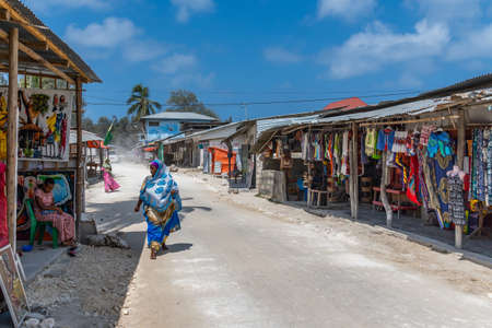 Zanzibar, Tanzania - February 8. 2020: street view with a woman and shops in the fishing village of Nungwi. Zanzibarのeditorial素材
