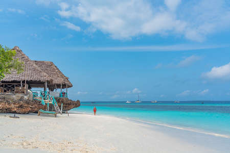 Nungwi Beach, Zanzibar-Tanzania, February 12, 2020: People at the tropical white Beach of Zanzibar Island. Turquoise ocean, blue cloudy sky, copy spaceのeditorial素材