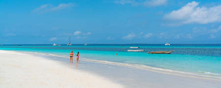 Nungwi Beach, Zanzibar-Tanzania, February 12, 2020 : People at the tropical white Beach of Zanzibar Island. Tanzania. Eastern Africa, turquoise Ocean, blue cloudy Sky, copy spaceのeditorial素材