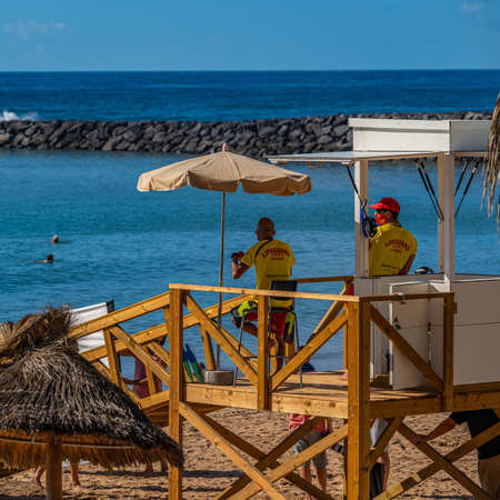 LOS CRISTIANOS, TENERIFE, CANARY ISLAND, SPAIN, DECEMBER 02. 2020: Playa del Camison beach. It is a small beach with straw parasols in Tenerife island, verticalのeditorial素材