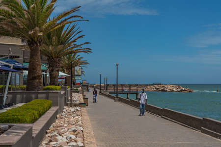 SWAKOPMUND, NAMIBIA - JAN 11, 2020: Promenade in Swakopmund with palm trees and people have rest at the walkingwayのeditorial素材
