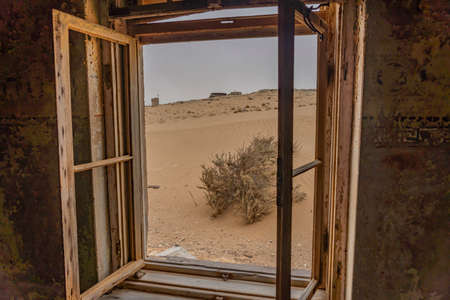 View out of a window at German Kolmanskop - Kolmannskuppe Ghost Town in Namibia with the abandoned buildings in the Namib desertの写真素材