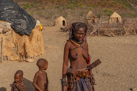 KHORIXAS. NAMIBIA, JANUARY 13. 2020: Himba tribe woman with two boys in the village of Himba people,...