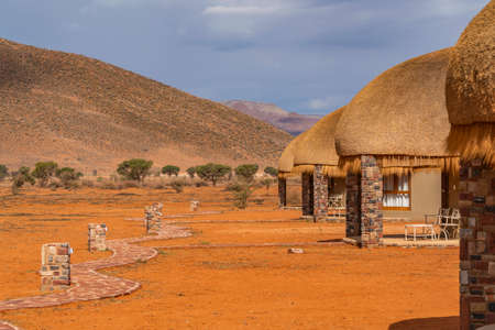 NAMIB NAUKLUFT PARK, NAMIBIA - JANUARY 06. 2021: Walking way at the thatched roof house at the We Kebi Safari Lodge in Namib Naukluft National Parkのeditorial素材