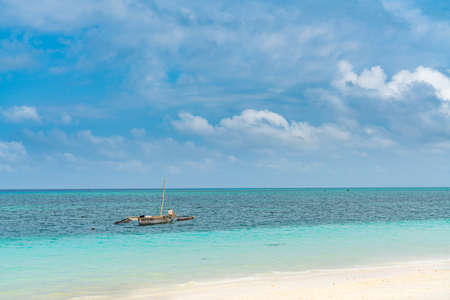 A Boat at the tropical white beach of Zanzibar island. background blue sky with clouds, Tanzania.の写真素材