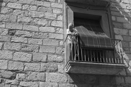 Black and white street picture of a old woman on a balkonyのeditorial素材