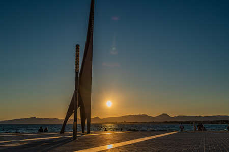 SALOU, SPAIN - SEPTEMBER 19.2021: Sunset with silhouette of people and sculpture at the coastline Costa Dorada, promenade Salou, Spain.のeditorial素材