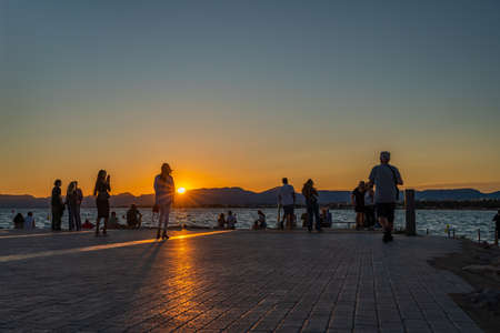 SALOU, SPAIN - SEPTEMBER 19.2021: Silhouette of people watching sunset at the coastline Costa...