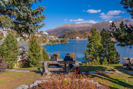 SANKT MORITZ, SWITZERLAND - OCTOBER 28,2022: A couple on a banch in St. Moritz with the lake St. Moritz in autumn, background the mountainsの写真素材