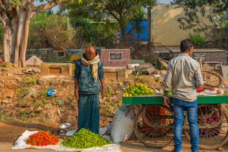 A man selling red and green chili peppers on the local Indian vegetable market in Puttaparthiのeditorial素材