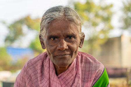 Indian old lady close up looking in the camera at a vegetable market in Puttaparthiのeditorial素材