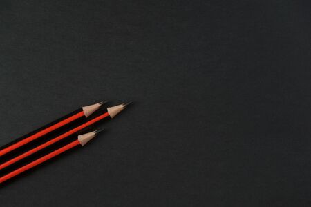 Three lead pencil with black and red stripes on a dark background to spiral upwards like a rocket