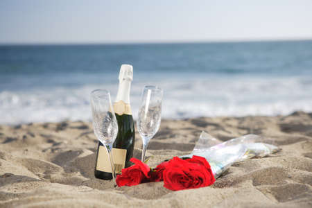 Champagne Bottle, Glasses, Roses at the beach on the sandの写真素材