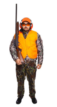 Portrait of a typical hunter holding a pump action shotgun, while wearing safety and camouflage...