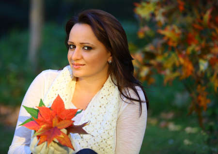 Autumn woman sitting and smiling with leaves