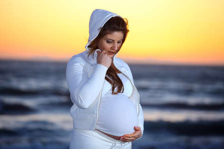 Pregnant woman at the Beach with jacket and hoodの写真素材