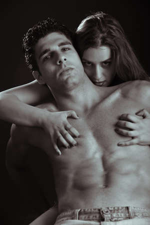 Young couple holding each other on black background