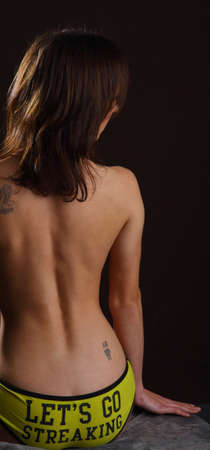 Nude woman's back wearing yellow panties with 'Let's go streaking" printed on the back.の写真素材