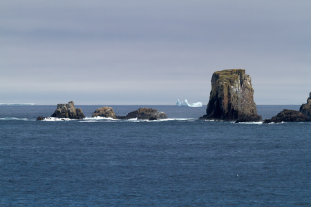 Atlantic coastline with rocks and iceberg.の写真素材