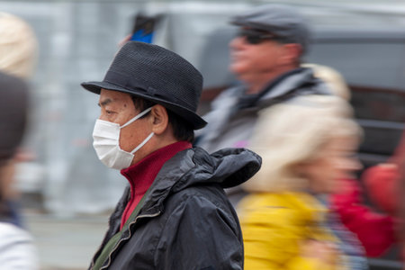 TALLINN, ESTONIA, JULY 5, 2018: An unidentified tourist wearing a medical mask moves through a group of people, taken in Tallinn on July 2, 2018.のeditorial素材