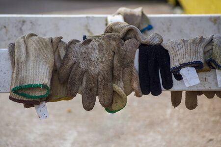 Used cotton work gloves hanging over a wooden rail.の写真素材