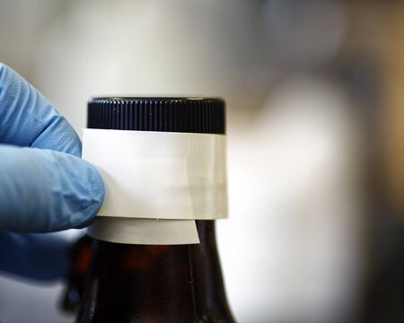Taping the cover on a chemical storage bottle to prevent vapor leakage.
