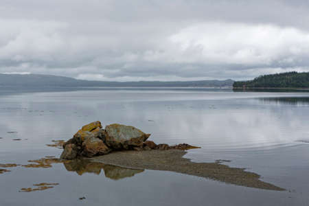 Rock reflection in the ocean on a cloudy day.の写真素材
