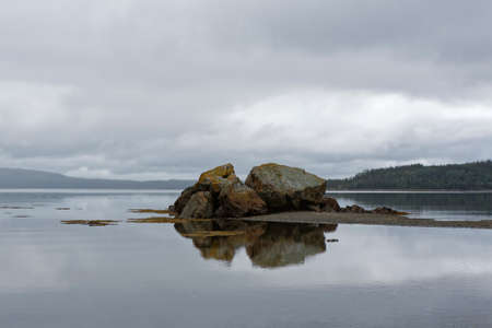 Rock reflection in the ocean on a cloudy day.の写真素材