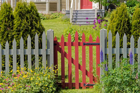 Brightly colored wooden gate with flowers and trees.の写真素材