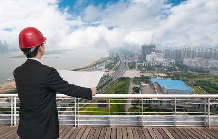 Rear view of architect looking comparing housing project with buildingの写真素材
