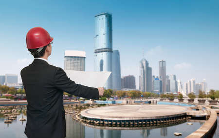 Rear view of architect looking and comparing housing project with building