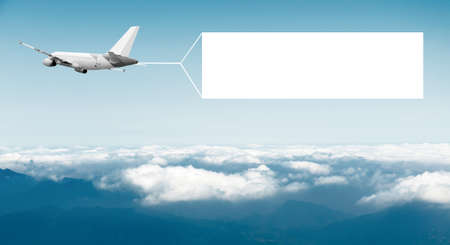 An airplane flying through the sky pulling a blank white banner to add your own message.の写真素材