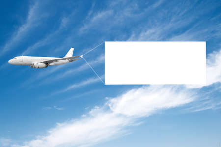 An airplane flying through the sky pulling a blank white banner to add your own message.の写真素材