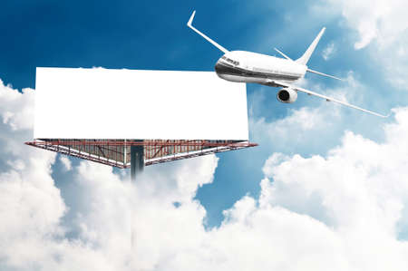 Big empty billboard with copy space for your image or text with an airplane flying on the sky, ideal for travel or vacation promotionsの写真素材