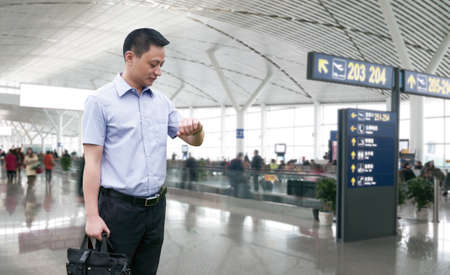 Young Businessman is waiting in the airport waiting hal and he checks the time on his watch.のeditorial素材