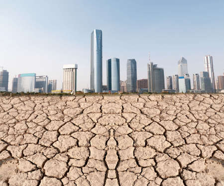 A city looks over a cracked earth landscapeの写真素材