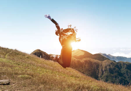 Happy Young Woman Jumping over blue sky. Beauty Girl Having Fun Outdoor. Freedom Concept. Nature. Green Fieldの写真素材