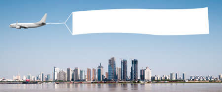 An airplane flying through the sky pulling a blank white banner to add your own message.の写真素材