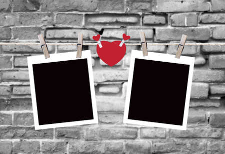 Blank instant photos and small red paper heart hanging on the clotheslineの写真素材