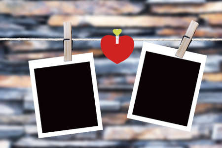 Blank instant photos and small red paper heart hanging on the clotheslineの写真素材