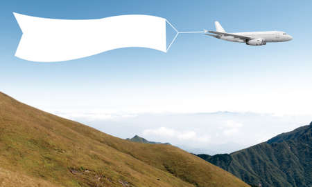 An airplane flying through the sky pulling a blank white banner to add your own message.の写真素材
