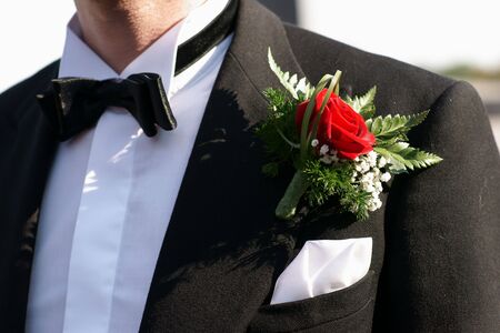 Red rose boutonniere on groom's wedding suitの写真素材