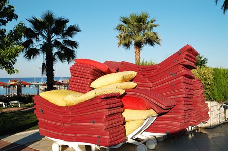 Stack of red sunbeds with plants and trees behindの写真素材