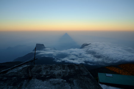 At sunrise, the triangular shadow of Adams Peak is cast over the landscape.
