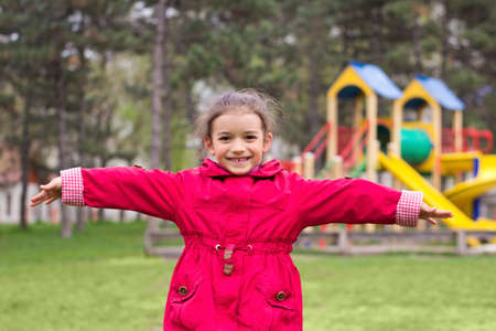 Little girl's portrait on playground. Child in red jacket in children's park in springの写真素材