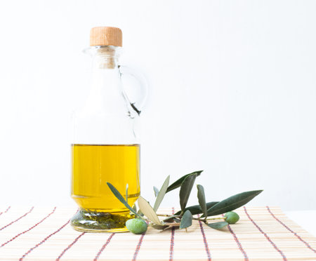 Glass bottle of olive oil and some olives with leaves isolated on a white background.の写真素材
