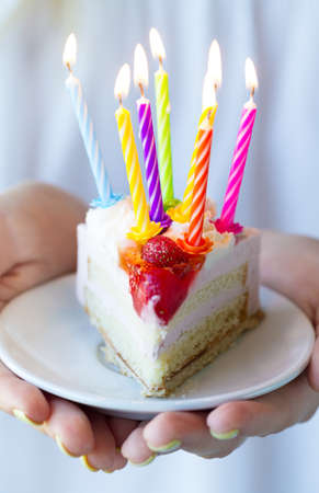 Girl holding beautiful appetizing birthday cake with many candles. Closeup.